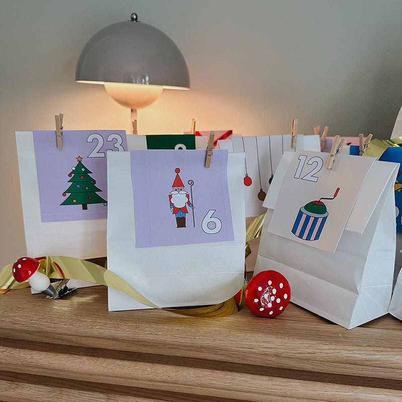 Weihnachtlicher DIY-Adventskalender mit Santa-, Tannenbaum- und Zahlenmotiven auf weißen Tüten – stilvolle Bastelidee in sanften Farben.