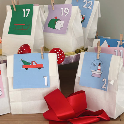 Weiße Adventskalender-Tüten mit nummerierten Karten und Clipanhängern in Pastellfarben – kreative Weihnachtsidee zum Selbstmachen.