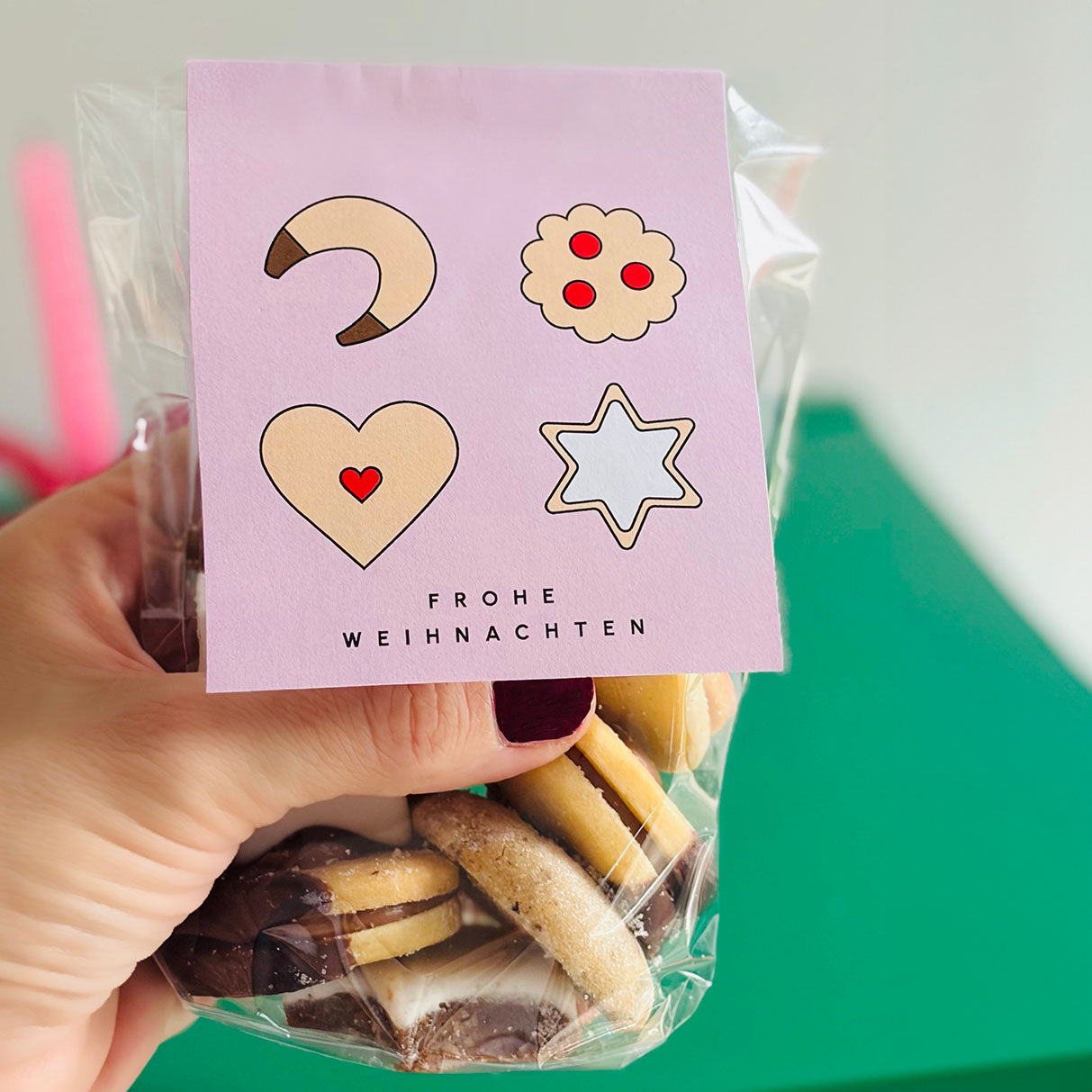 DIY Plätzchen-Anhänger in Pastelllila – moderne Druckvorlage mit Weihnachtskeksen, befestigt an einer Geschenk- oder Gebäck-Tüte.