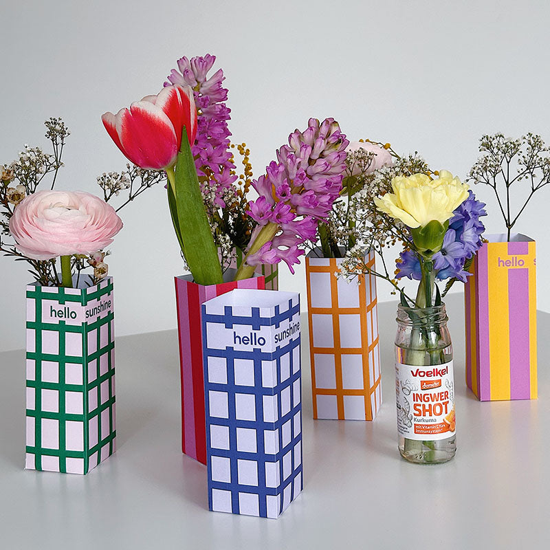 Buntes DIY Papier Vasen Set zum Ausdrucken und Basteln – moderne Blumenvasen aus Papier mit frischen Blumen dekoriert, inklusive Glasflasche im Inneren.