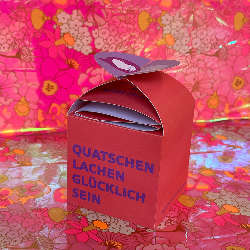 DIY Geschenkbox „Quatschen, lachen, glücklich sein“ – kreative Geschenkverpackung für Gutscheine vor floralem Hintergrund